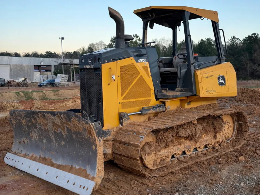 Dozer with a clay caked blade parked on a graded pad at dusk