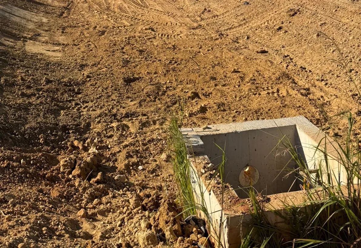Graded swale running down to a precast concrete outlet structure on a commercial site