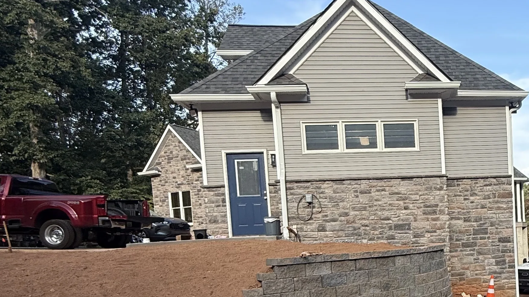 New house on a graded red clay lot with a block retaining wall along the drive