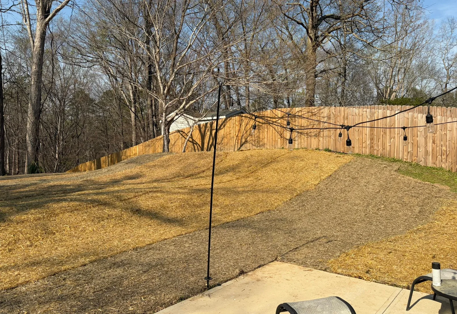 Regraded backyard slope covered in straw running back to a wood fence line