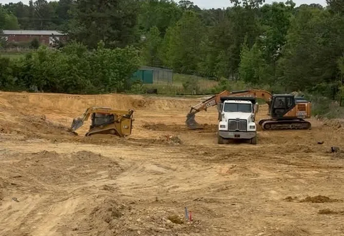 Dozer, dump truck and excavator working a wide dirt site during mass grading