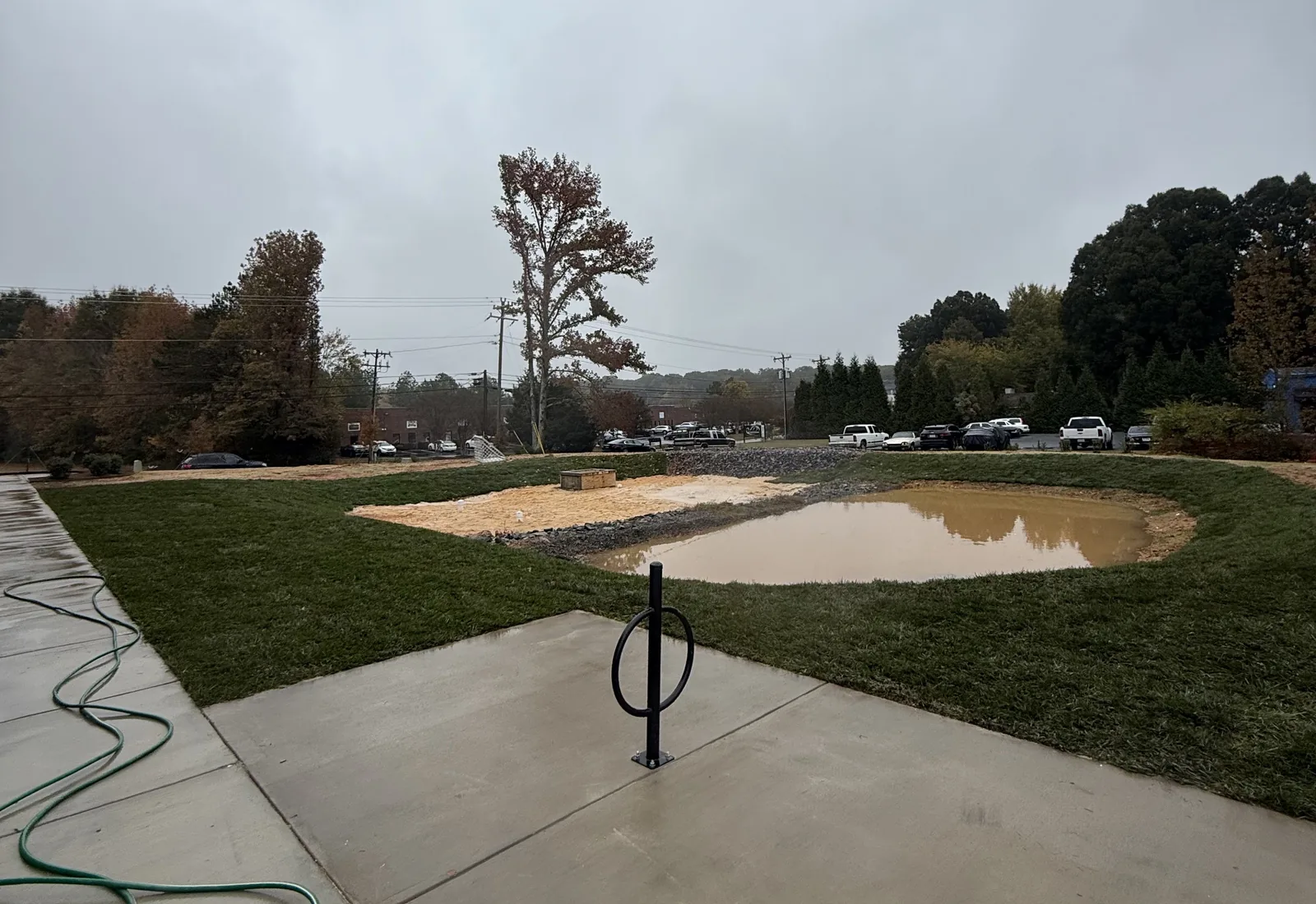 Stormwater basin holding water in a lawn beside a commercial building after rain