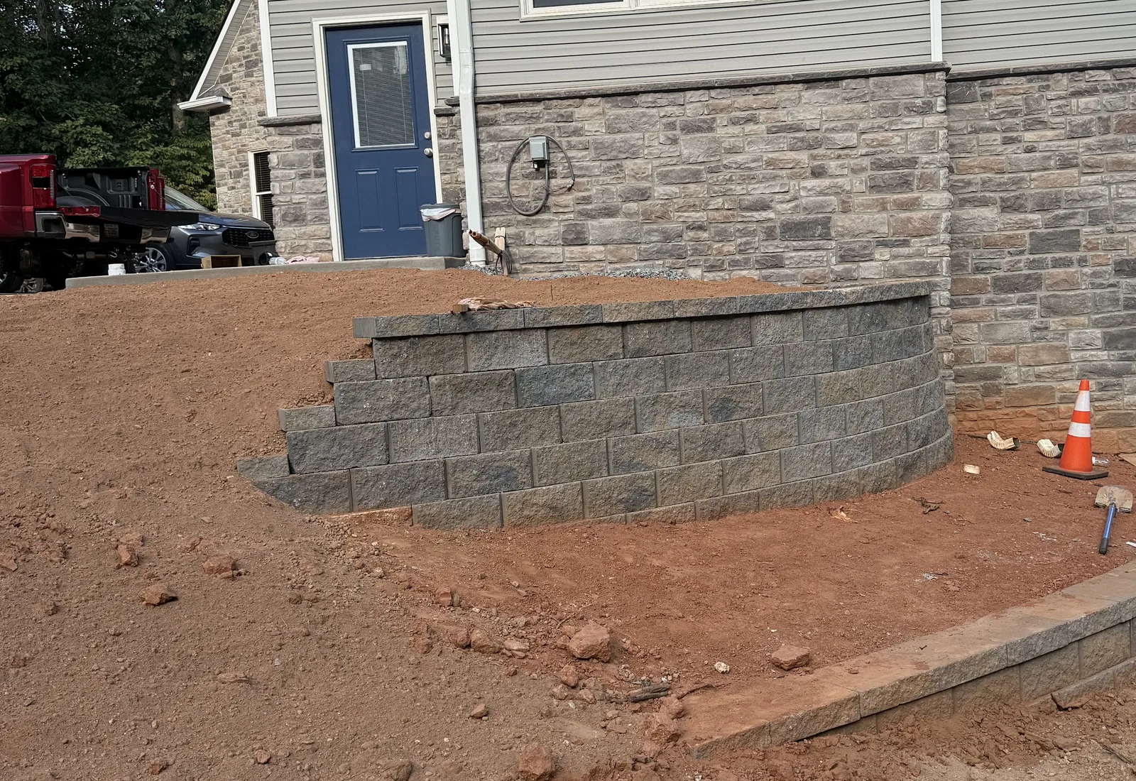Segmental block retaining wall with built in steps holding a graded slope beside a new house