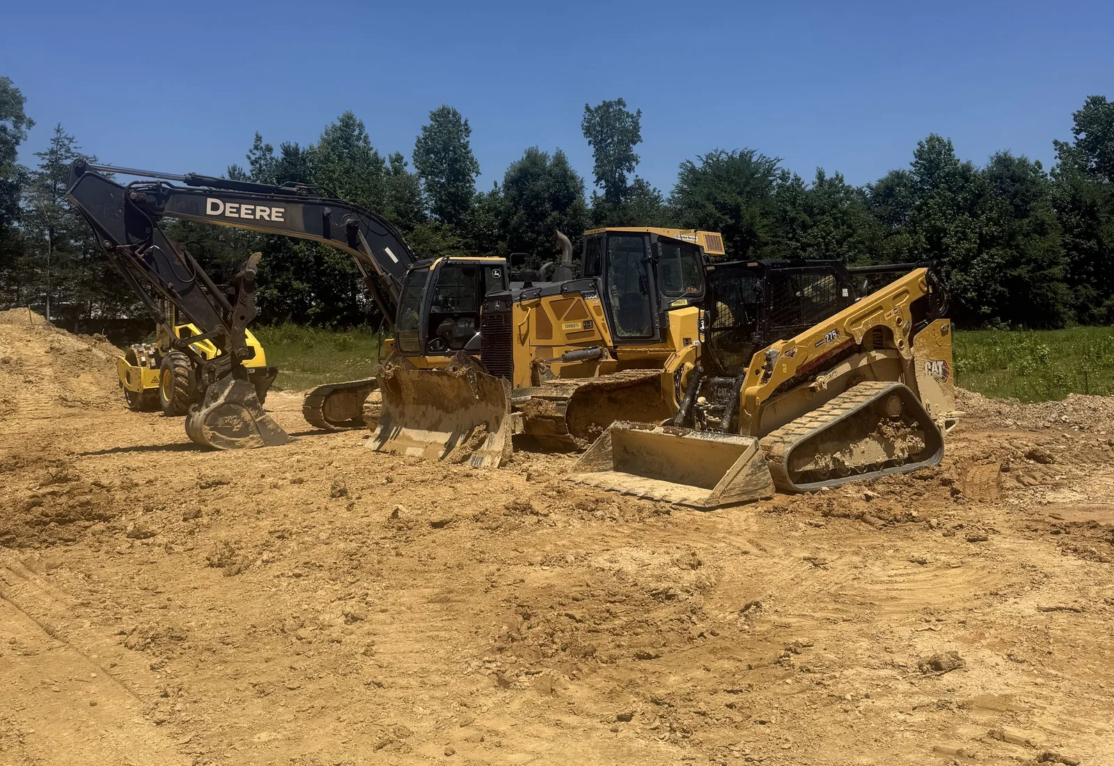 Excavator, dozer and compact track loader parked on a graded dirt lot