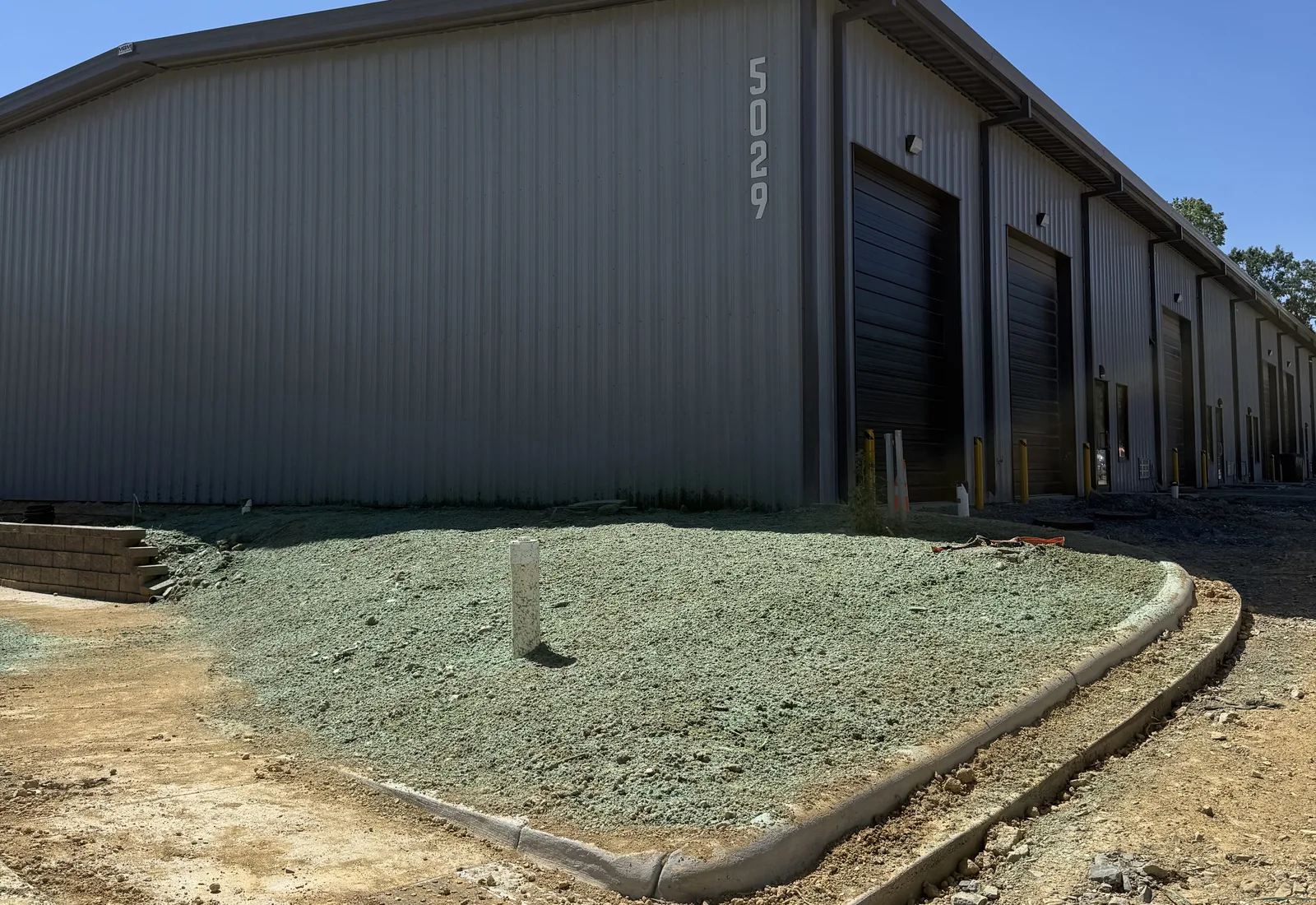 New metal building with a hydroseeded lawn, fresh curb and concrete apron around it